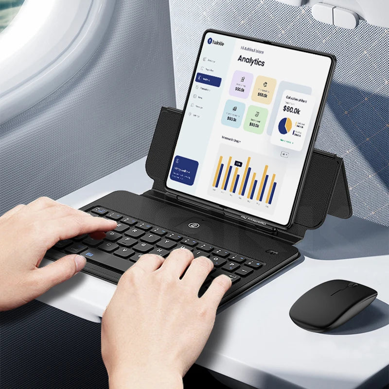 Person using a tablet with a keyboard and mouse on a car's tray table.