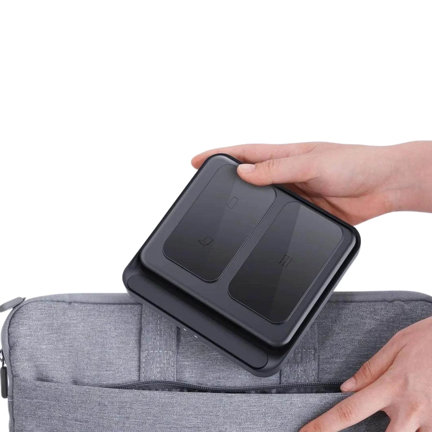 Hand placing black dual wireless charger into gray laptop bag with zipper